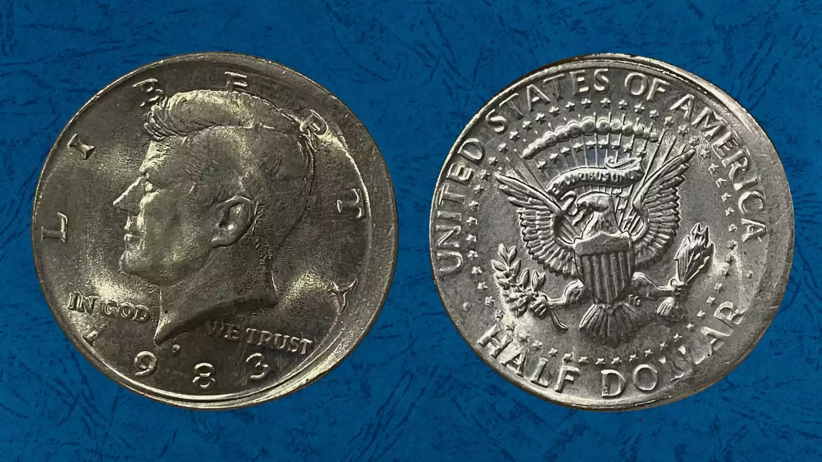 1983-P Kennedy Half Dollar broadstruck error showing expanded planchet diameter and distorted rim compared to normal coin